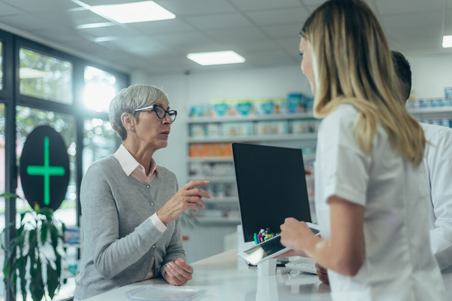 older woman talking to pharmacists at pharmacy counter