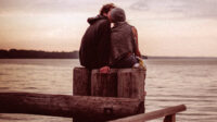 Photo of couple kissing on a pier at the sea