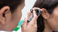 person checking patient's ear with otoscope
