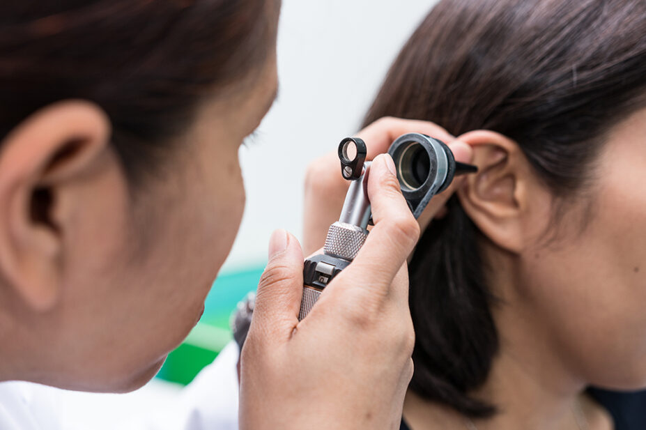person checking patient's ear with otoscope