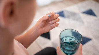 man holding prep pill and glass of water