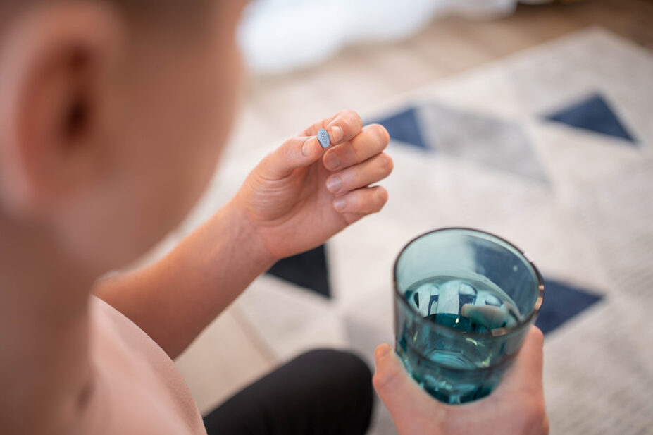 man holding prep pill and glass of water