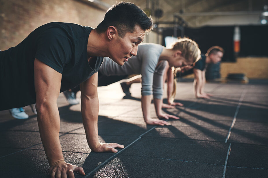 Group of people performing push ups on gym floor