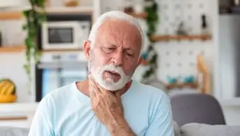 Close up of senior man rubbing sore throat or pained neck