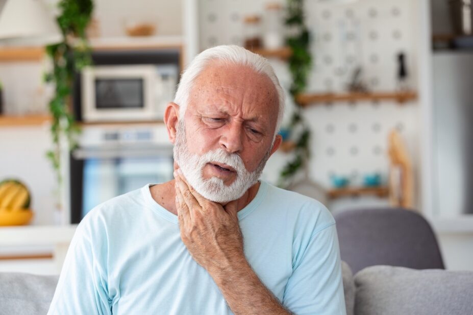 Close up of senior man rubbing sore throat or pained neck