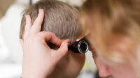 Physician checks child's ear with otoscope