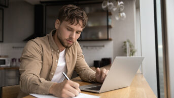 Adult male sitting at laptop at home studying