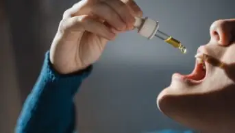 Photo of a woman dripping CBD oil to ingest sublingually