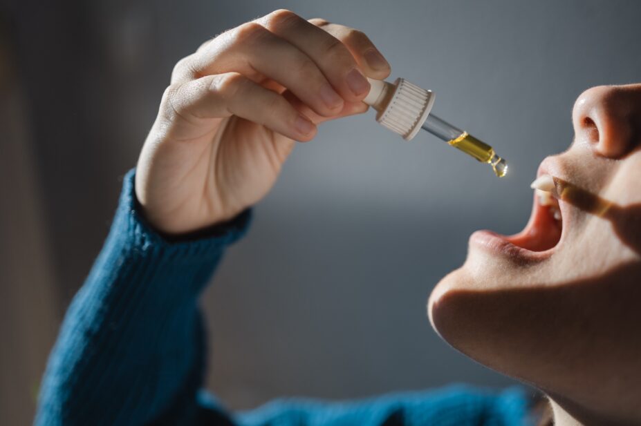 Photo of a woman dripping CBD oil to ingest sublingually