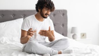 Unhappy millennial Indian guy suffering from heartburn