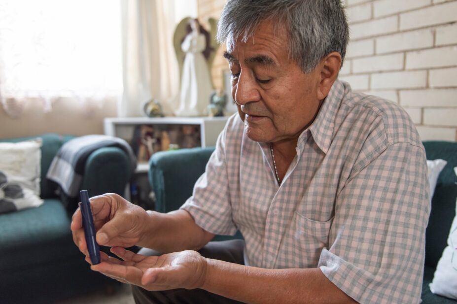 Photo of an elderly adult with diabetes pricking a finger to draw blood to measure his sugar levels from home