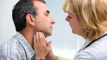 healthcare professional touching patient's throat to examine it