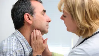 healthcare professional touching patient's throat to examine it