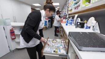 young pharmacist looking in medicines drawer