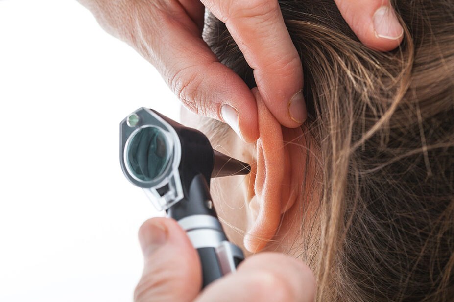 Close-up of examining ear with an otoscope
