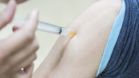 Doctor gives an intramuscular injection in a male arm