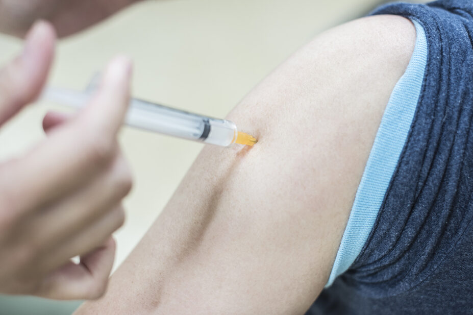 Doctor gives an intramuscular injection in a male arm