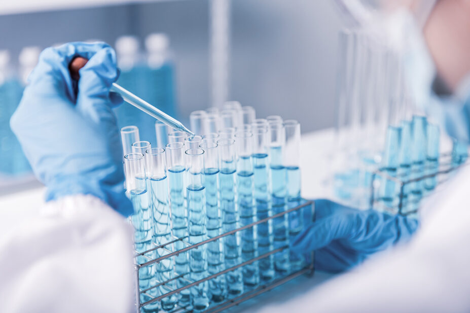 scientist hand dropping chemical liquid into test tube in lab