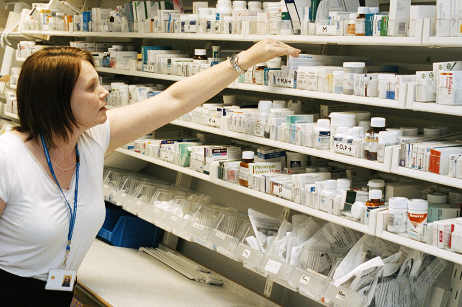 pharmacist reaching for medicine on shelf