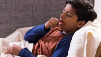 Young boy lying on the couch and coughing