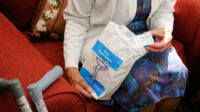 Older woman taking medicine box out of prescription bag
