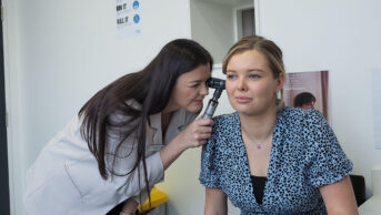 Pharmacist using otoscope to look in patient's ear