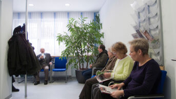 gp waiting room with patients sat down