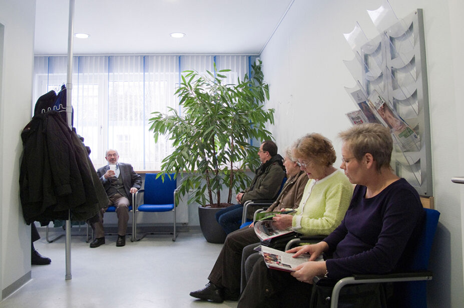 gp waiting room with patients sat down