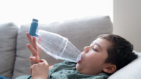Young boy using inhaler with spacer