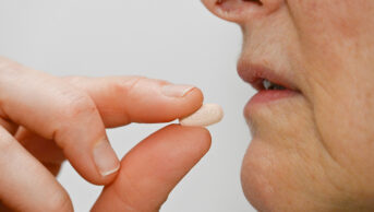 female patient taking an oral osimertinib tablet labelled AZ80