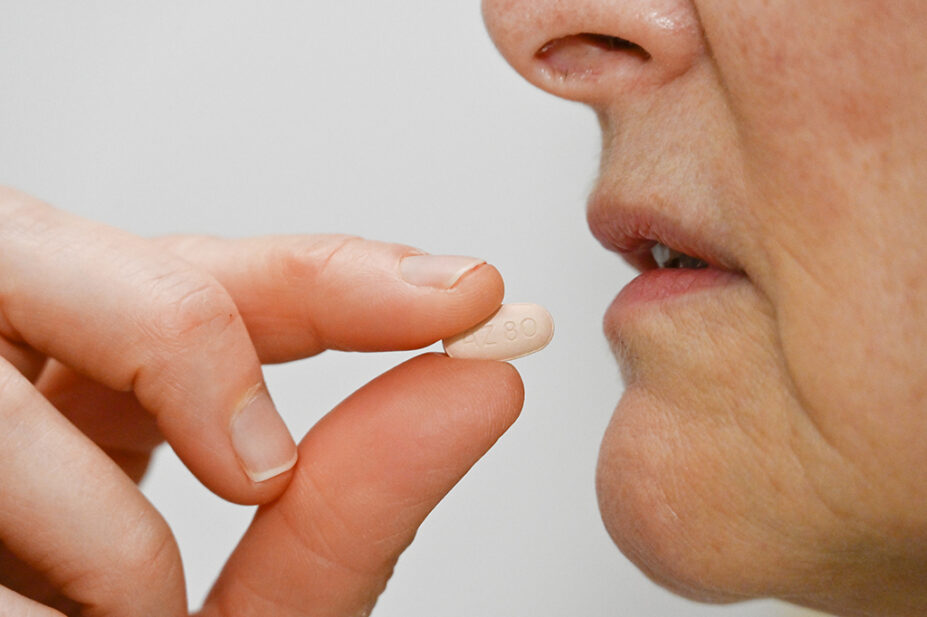 female patient taking an oral osimertinib tablet labelled AZ80