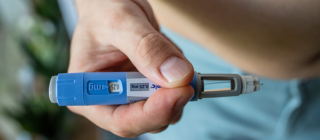 man holding semaglutide injection near stomach