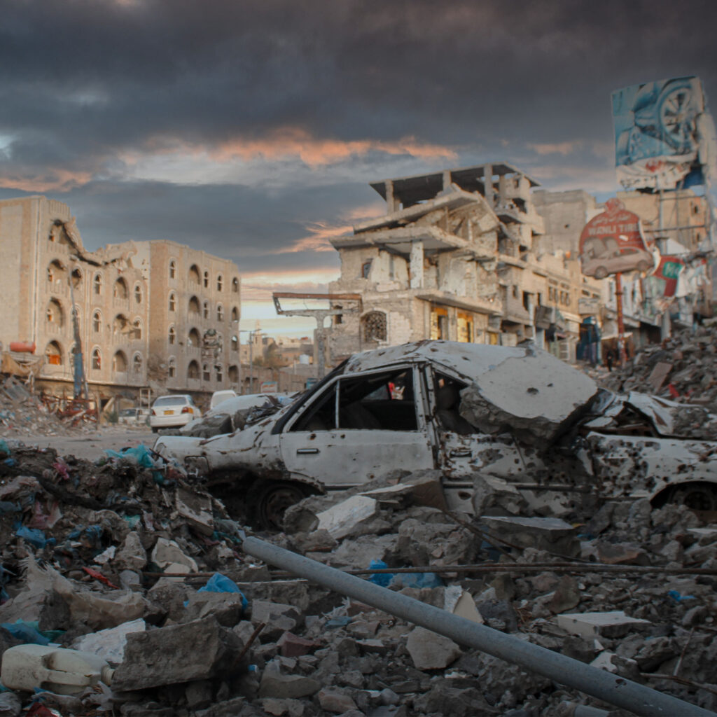 Photo of a bombed out car and rubble on a street in Taiz City, Yemen, 2015