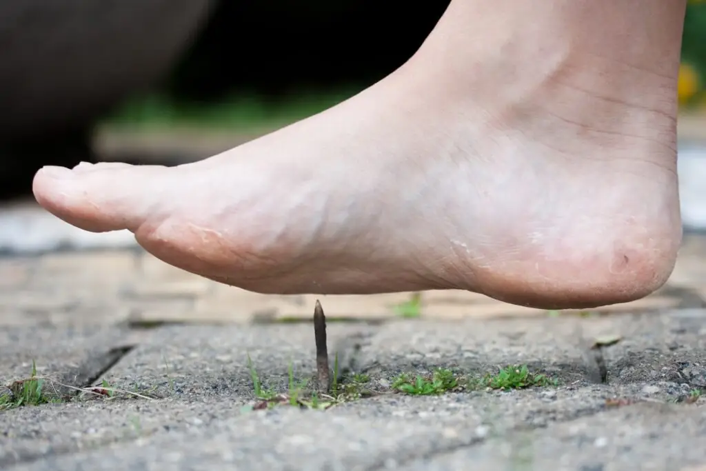 Foot stepping on rusty metal nail outdoors