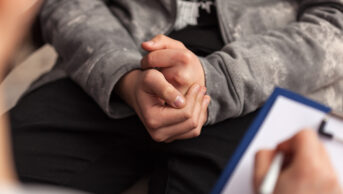 Young teenager in medical consultation, showing hands clasped together