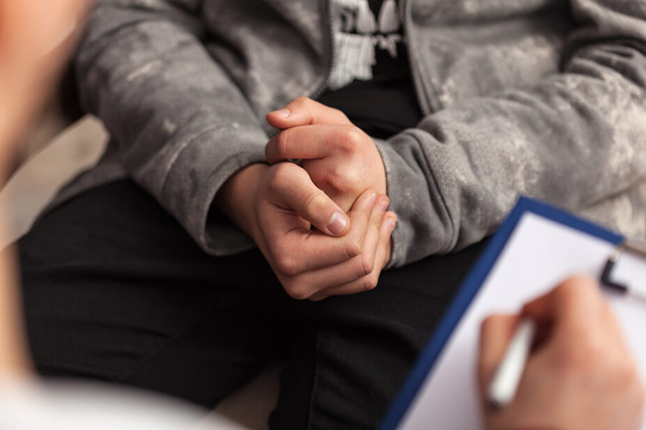 Young teenager in medical consultation, showing hands clasped together