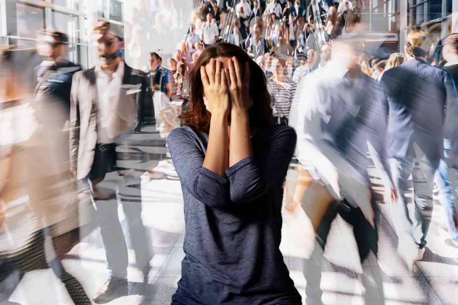 Crowd of people walking on a street in London in a blur, with a woman still, confused, in the middle