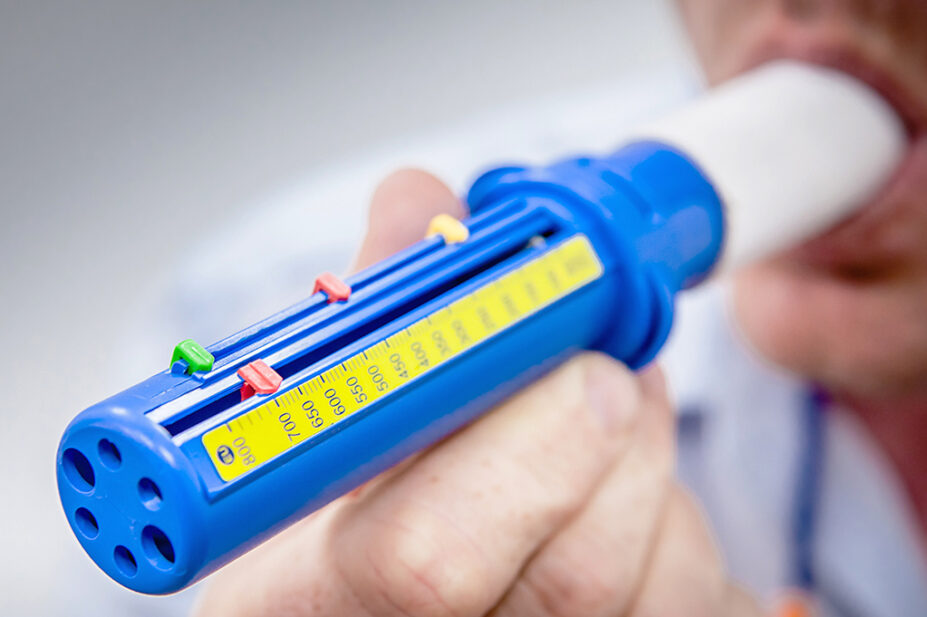 A man blows into a peak flow meter