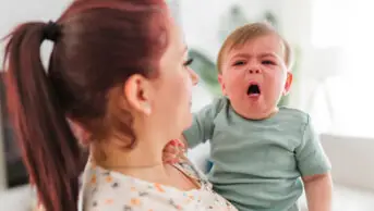 A mother holding a baby who is violently coughing