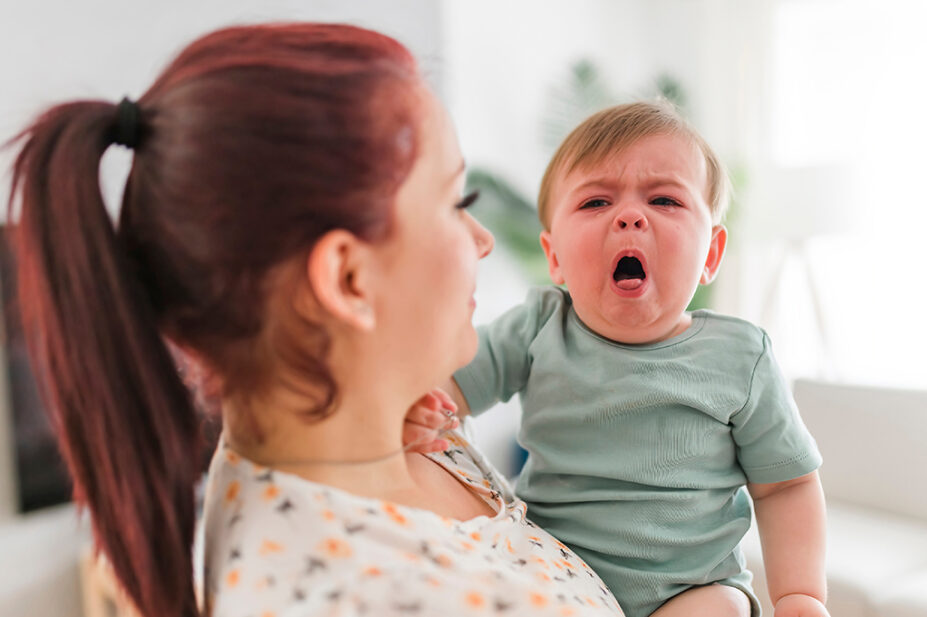 A mother holding a baby who is violently coughing