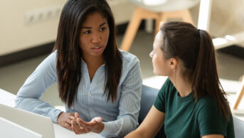 A supervisor helping a student with her work