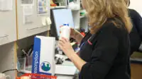 Female pharmacist examining a medication bottle at a workspace