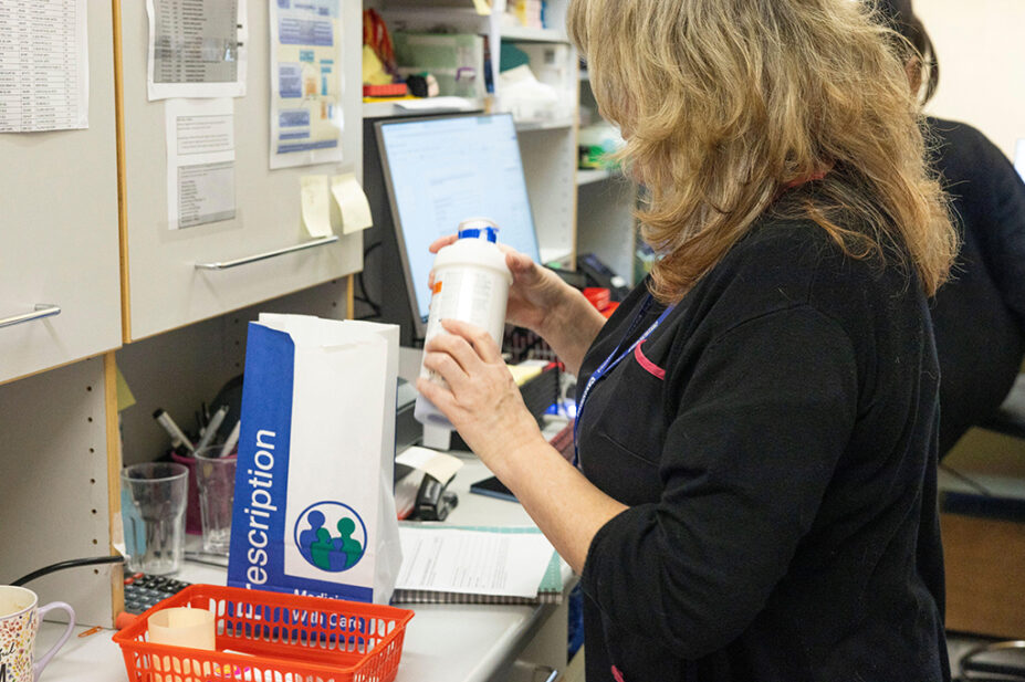 Female pharmacist examining a medication bottle at a workspace