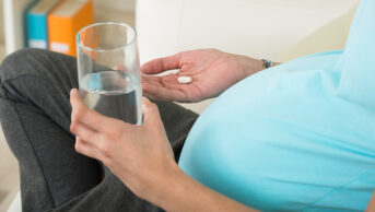 A pregnant woman taking a tablet
