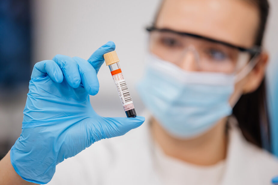 Someone working in a laboratory with a blood vial