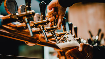 Someone pouring beer from bar tap