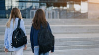 Two students wearing backpacks walking in university grounds