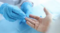 Close up of clinician carrying out finger prick test to identify diabetes