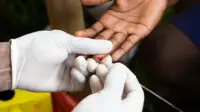 Health worker doing finger prick test to draw blood