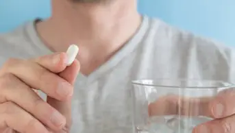 Man taking tablet with glass of water